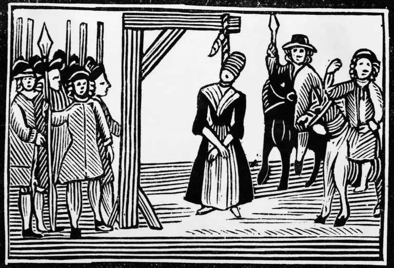 Old engraving of a supposed witch, blindfolded and hanging from gallows, onlookers standing by with pikes and lances